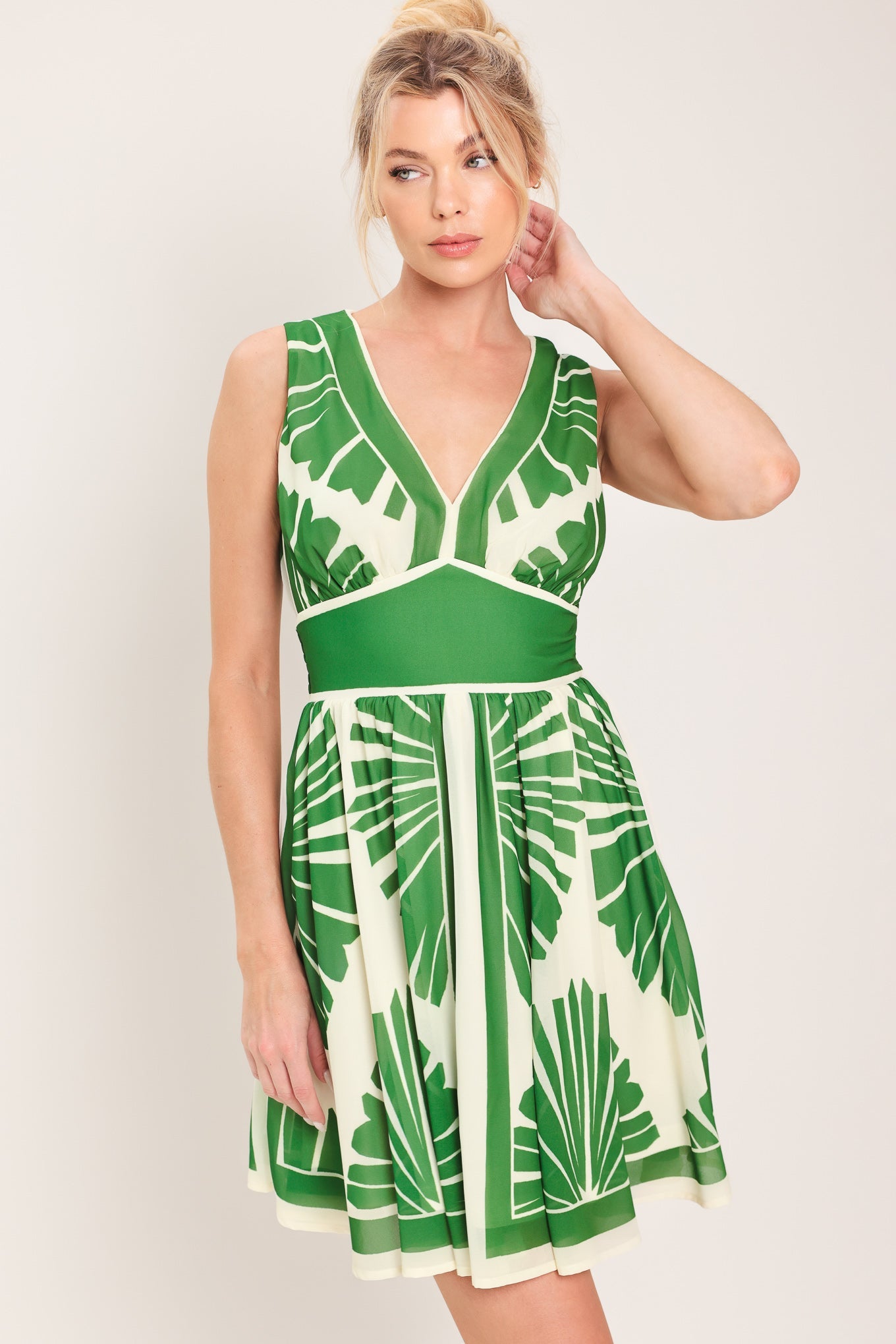 Woman wearing a green and white patterned dress against a plain background