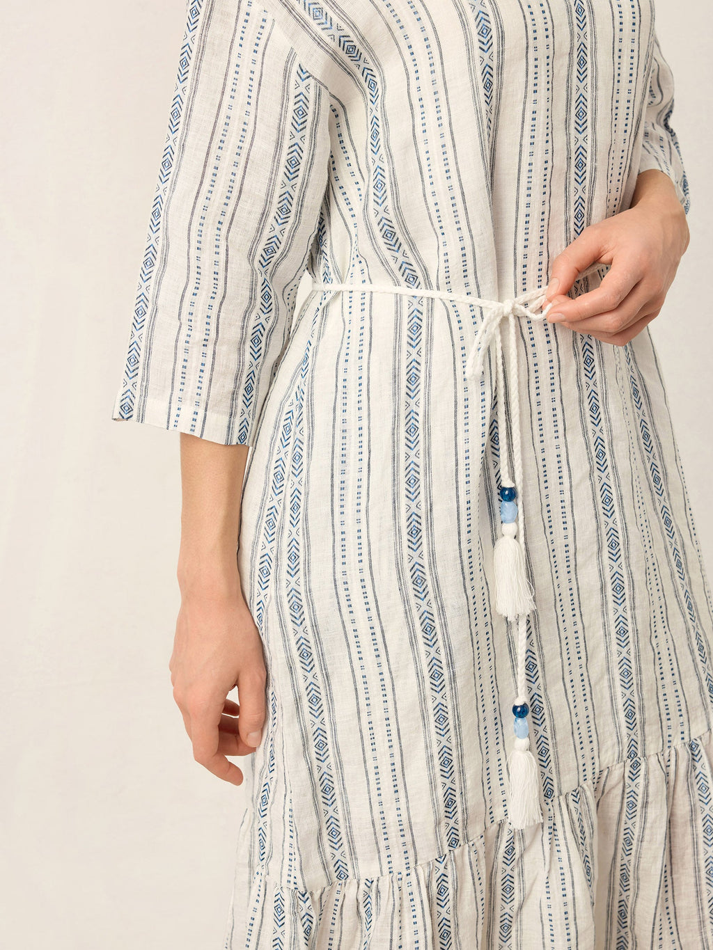 Person wearing a long, patterned dress with a neutral background