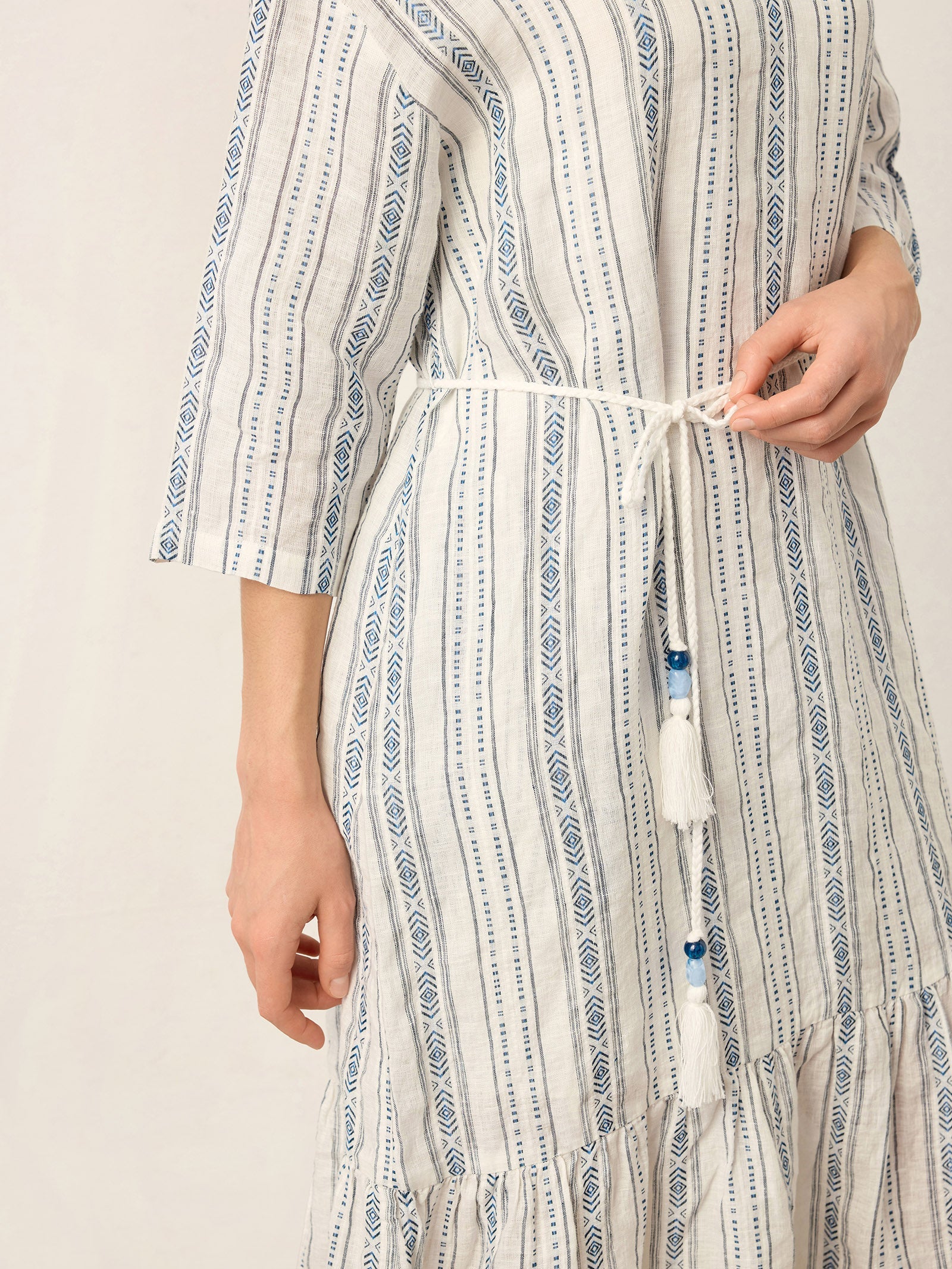 Person wearing a long, patterned dress with a neutral background