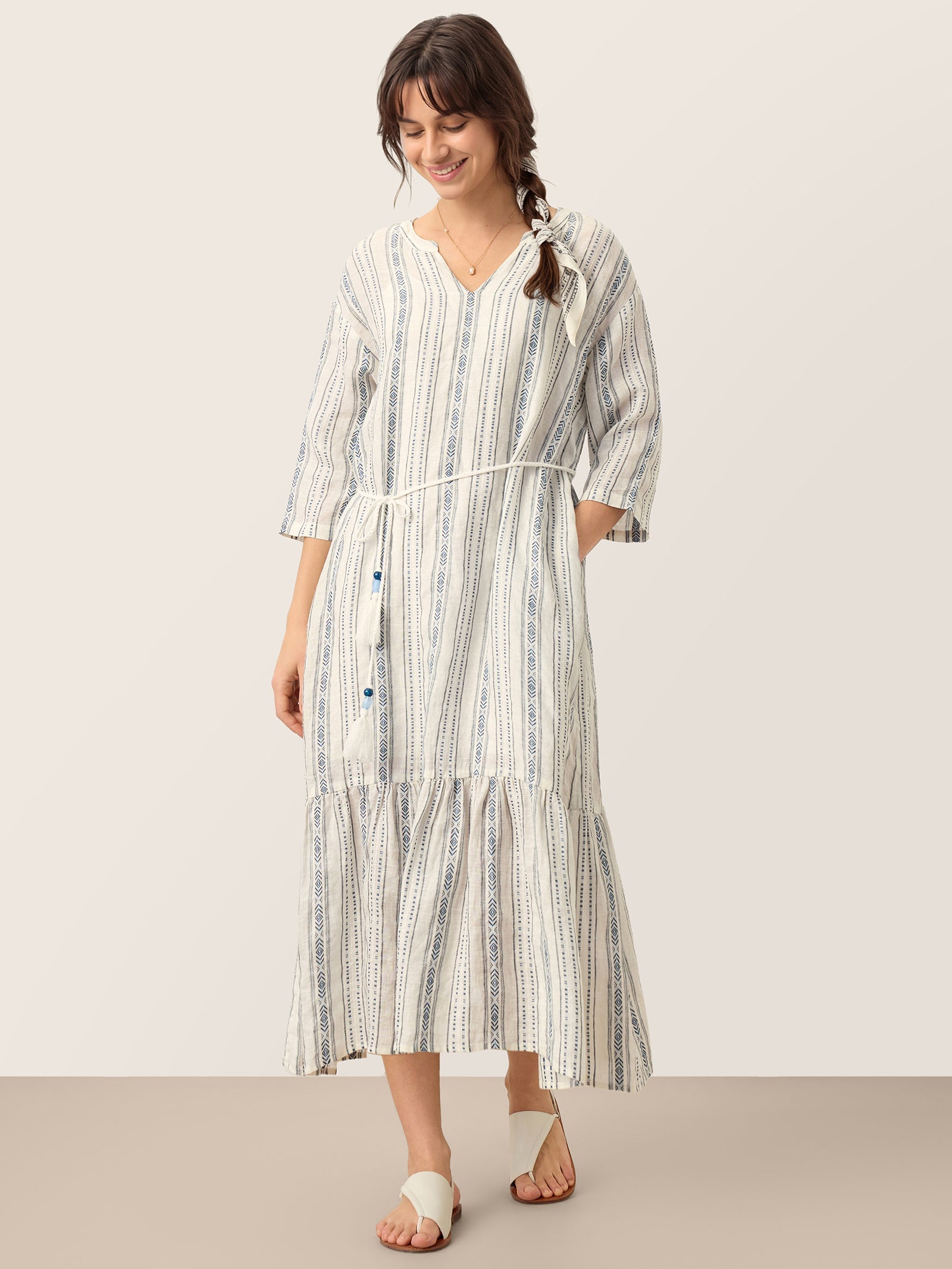 Woman wearing a long, striped dress against a plain background