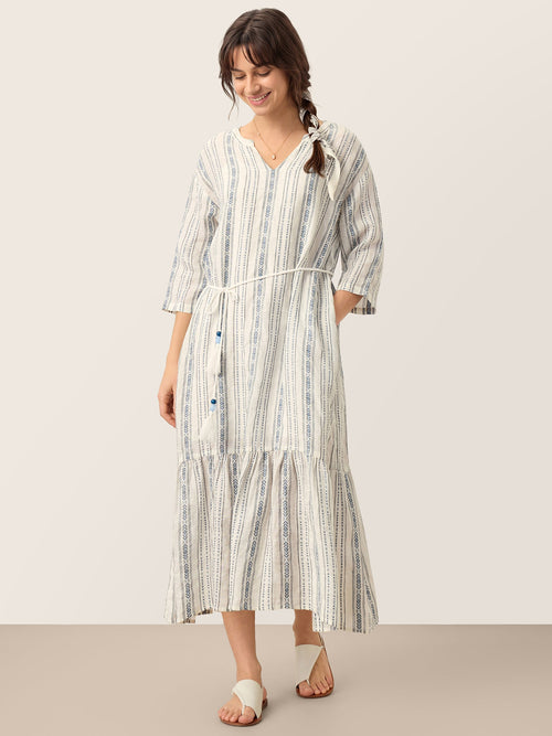 Woman wearing a long, striped dress against a plain background