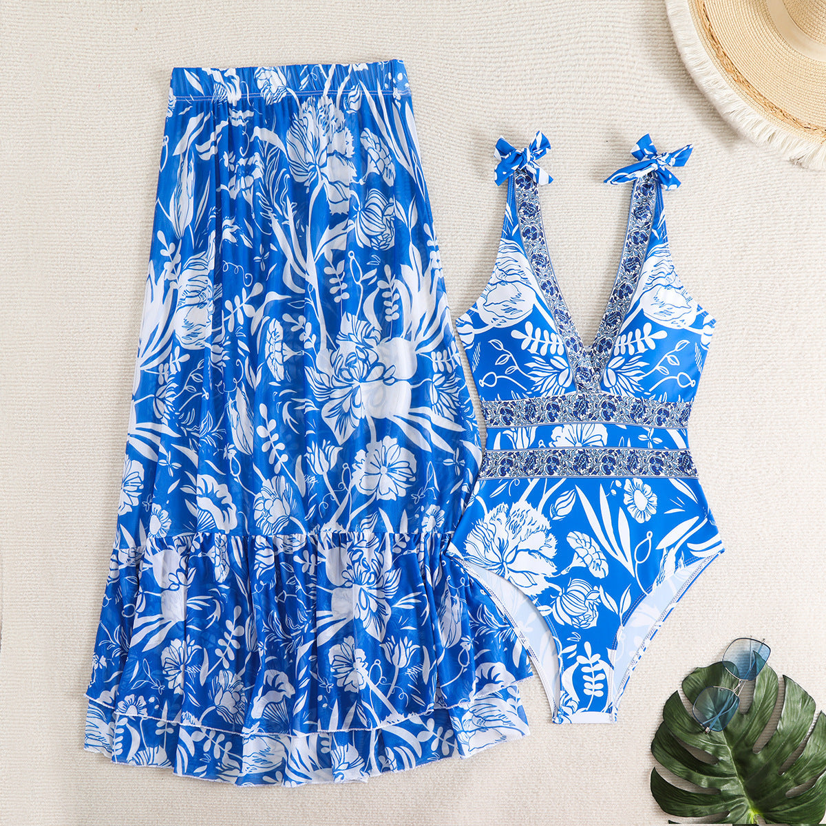 Blue and white floral swimsuit and skirt set on a white textured background