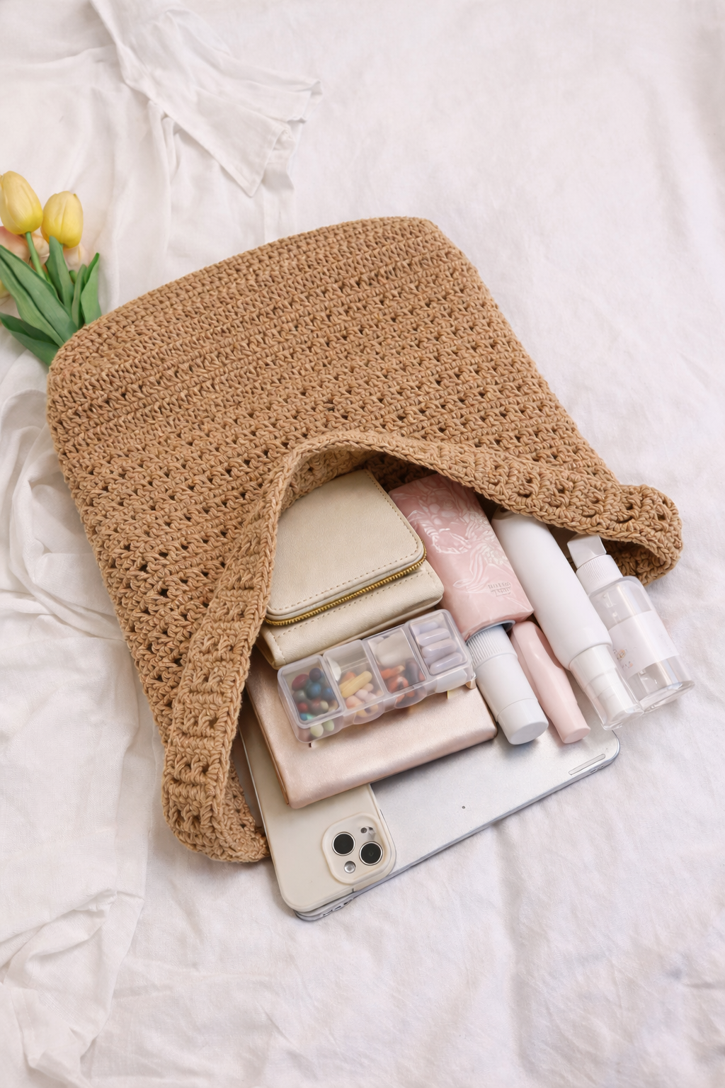 Crocheted bag with phone, makeup items, and a phone case on a light background