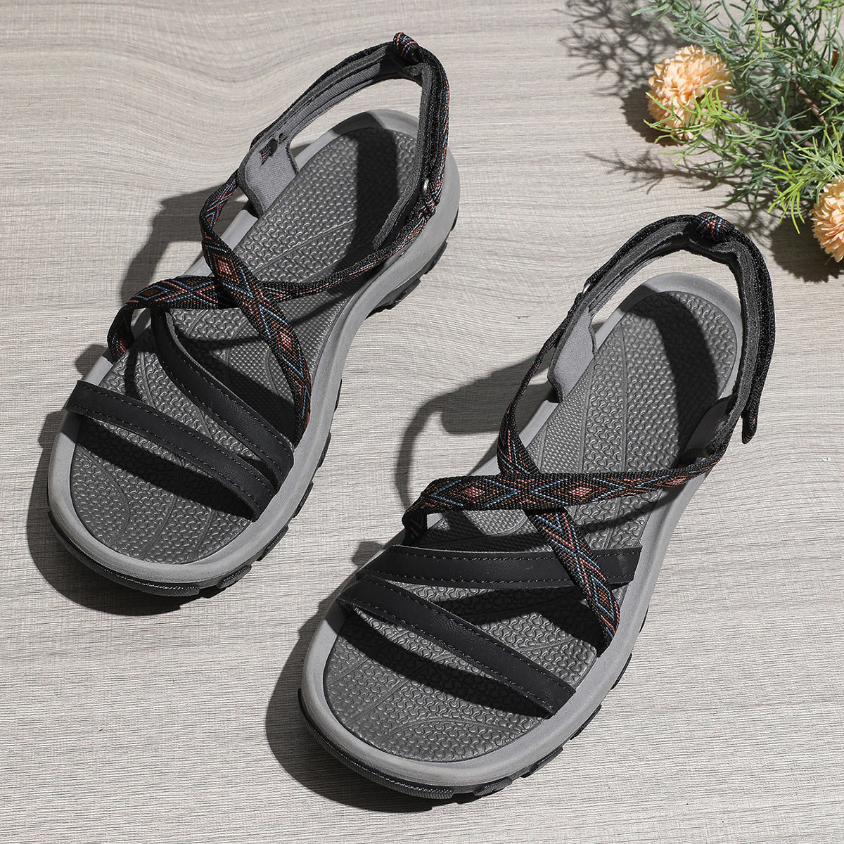 Pair of gray sandals with black straps on a textured surface.