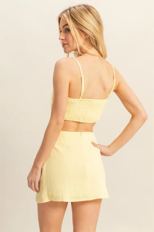 Woman wearing a yellow two-piece outfit against a beige background