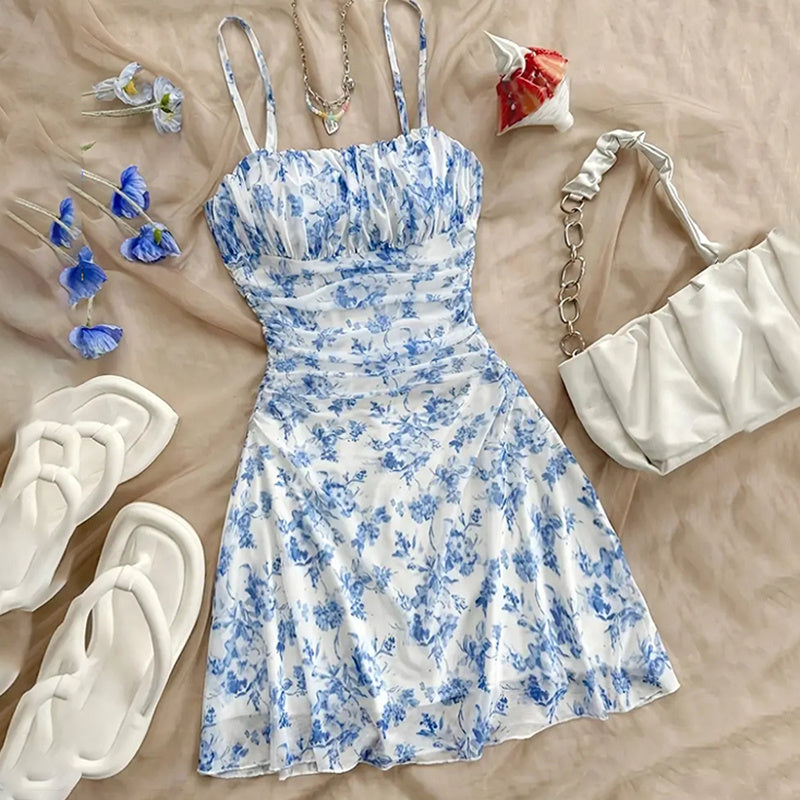 Blue and white floral dress with accessories on a beige surface
