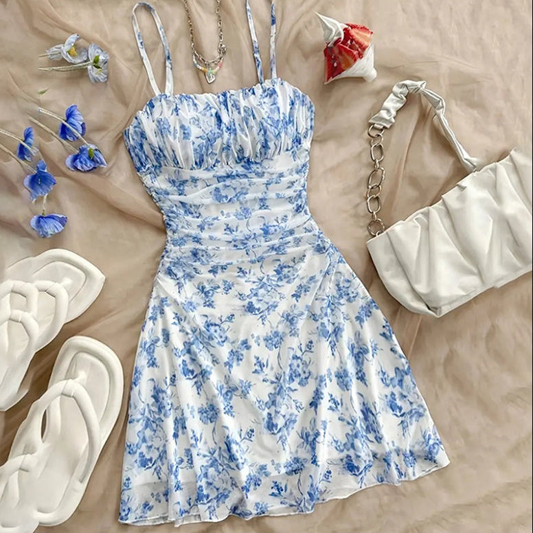 Blue and white floral dress with accessories on a beige surface