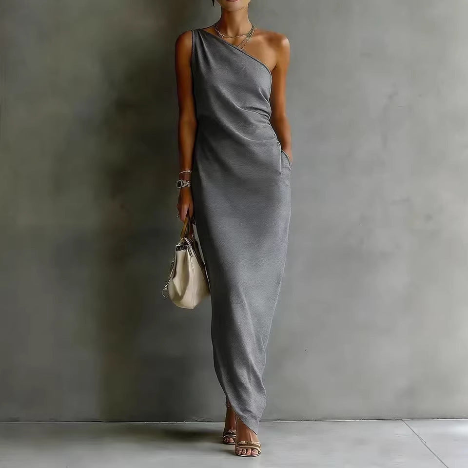 Woman wearing a gray one-shoulder dress against a plain background