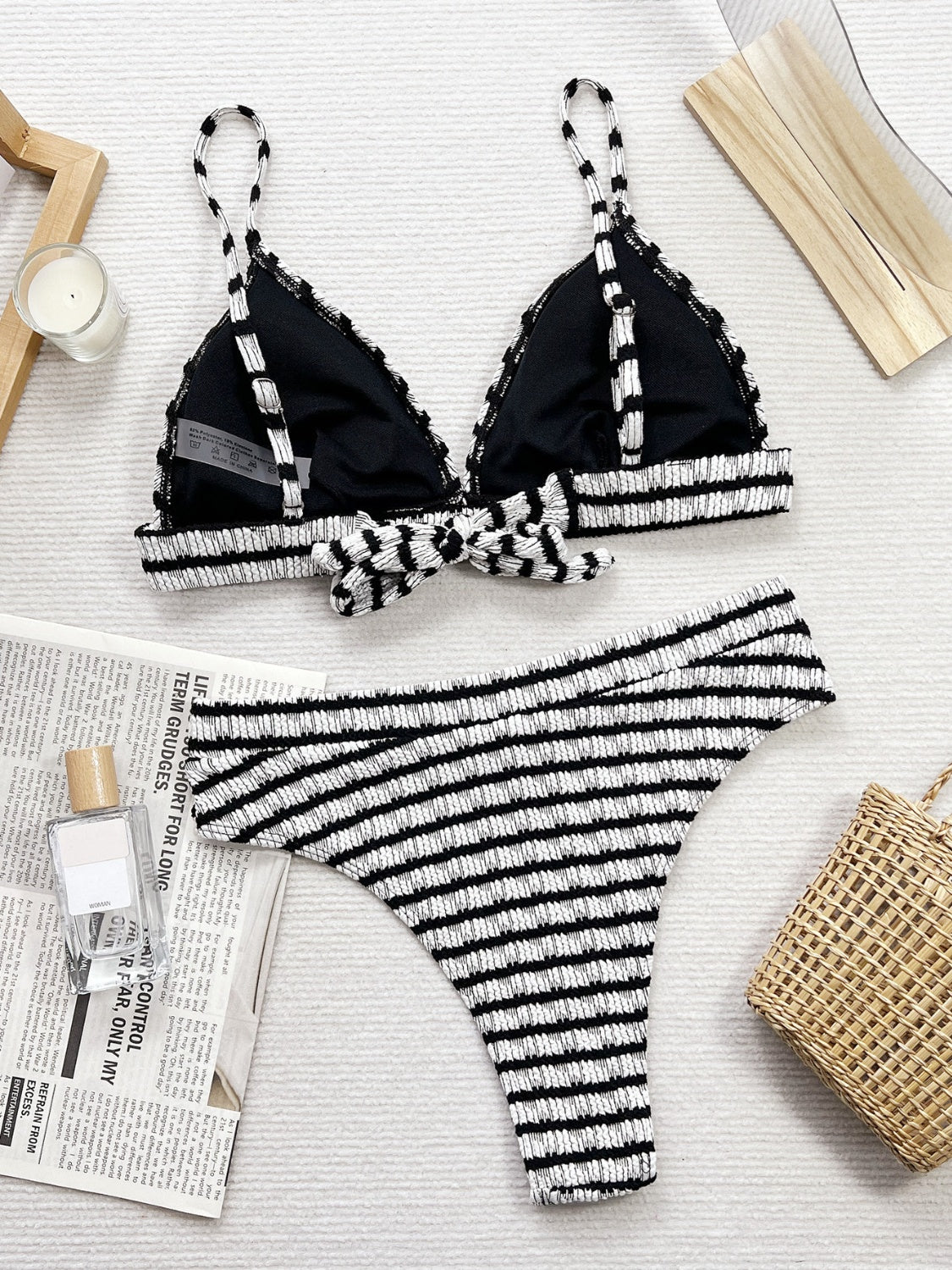 Black and white striped bikini set on a light surface with newspaper and basket in the background