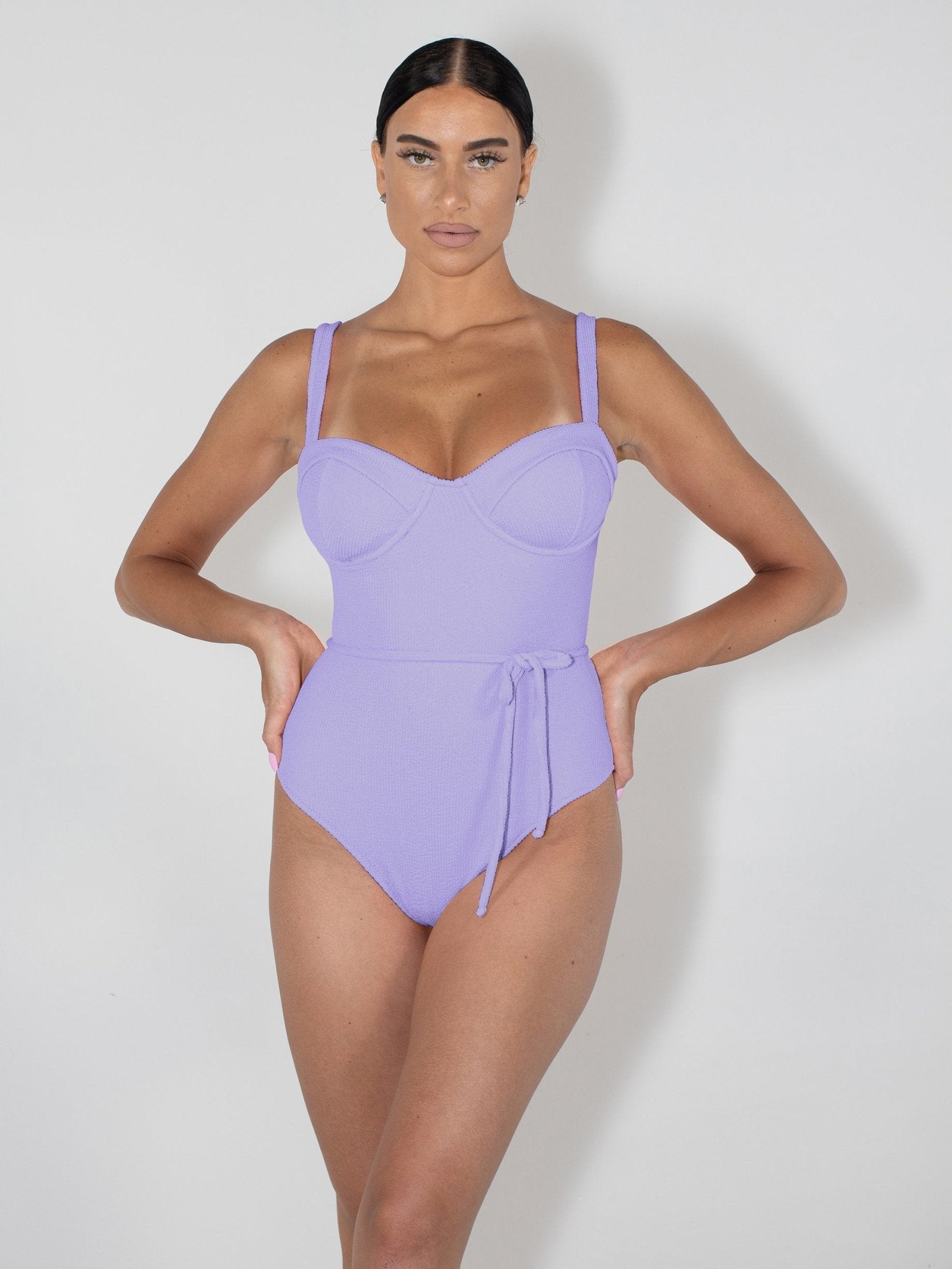 Woman wearing a purple swimsuit against a white background